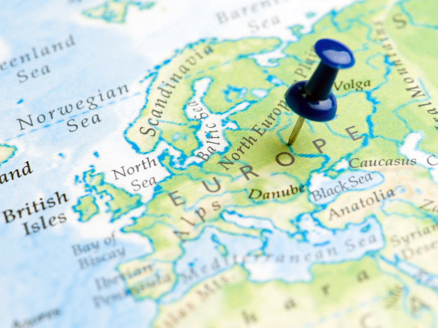 Nærbillede af Europakort med en blå knappenål markeret på kortet.
